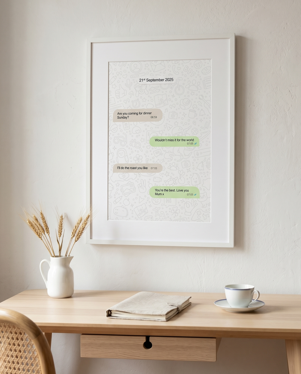 Framed text art on a wall above a wooden desk with a cup and vase.